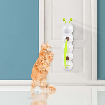 Orange kitten playing with a white wall-mounted spinning smart cat toy with suction cups and green feather on a door surface
